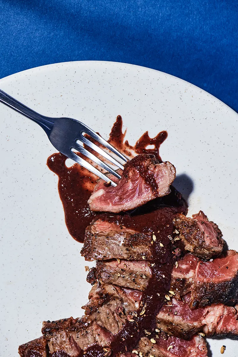 Sliced beef steak with hot sauce on a fork